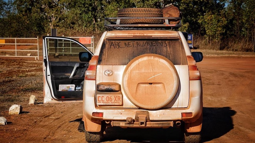 ABC News car covered in red dust with news website address written on window at 2017 Garma Festival.