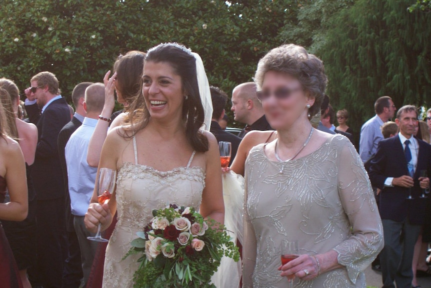 A new bride in a wedding dress posing with a guest after the ceremony.