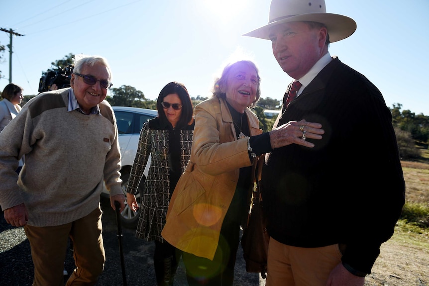 Barnaby Joyce looks away as his elderly mother reaches up to hug him. Behind them are his wife and his elderly father