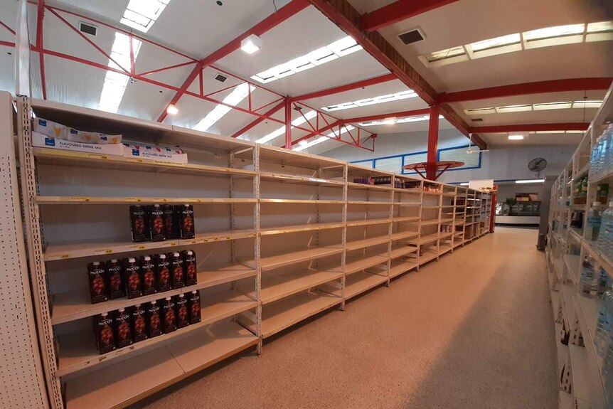 A photo of a supermarket with shelves almost completely empty