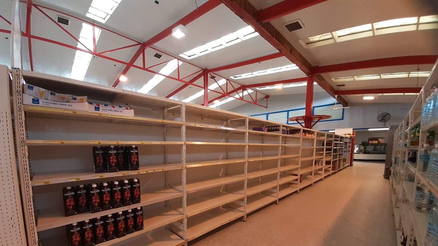 A photo of a supermarket with shelves almost completely empty