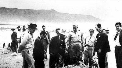 Scientists and military officials survey the site of the first atomic blast.