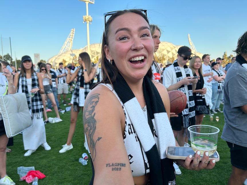 A woman in a Collingwood scarf shows her 