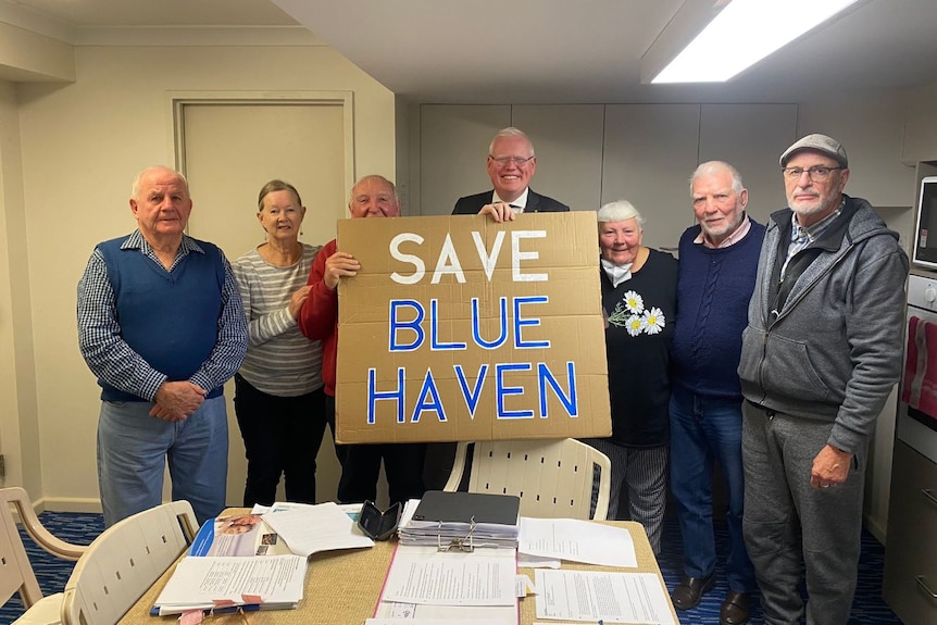 Seven people standing together holding a sign that reads 'Save Blue Haven'