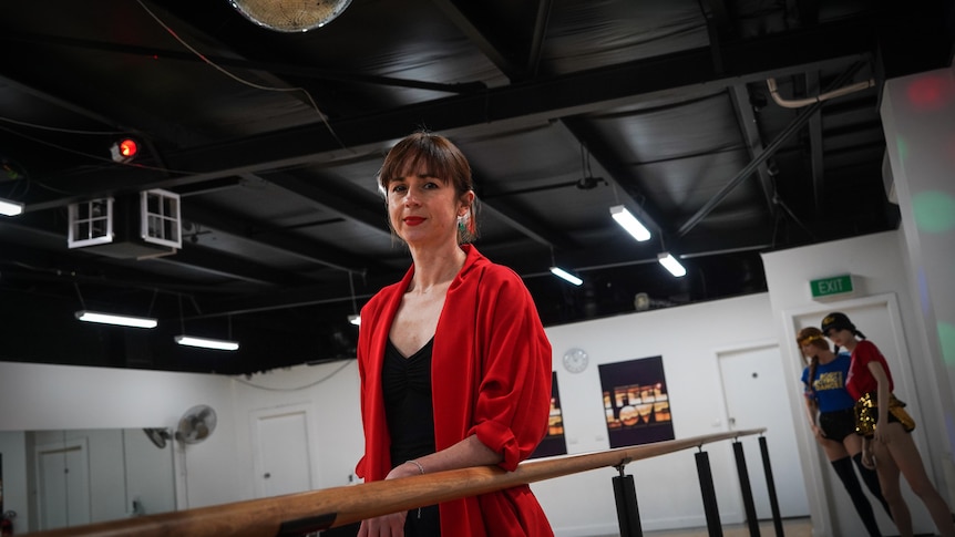 Jade Duffy, in a red blazer, stands in a dance studio looking at the camera.