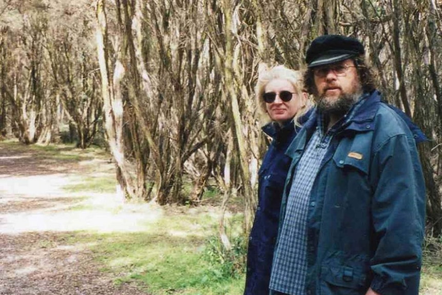 Terri Eskdale and Mark Brennan stand on a walking track in bushland together.