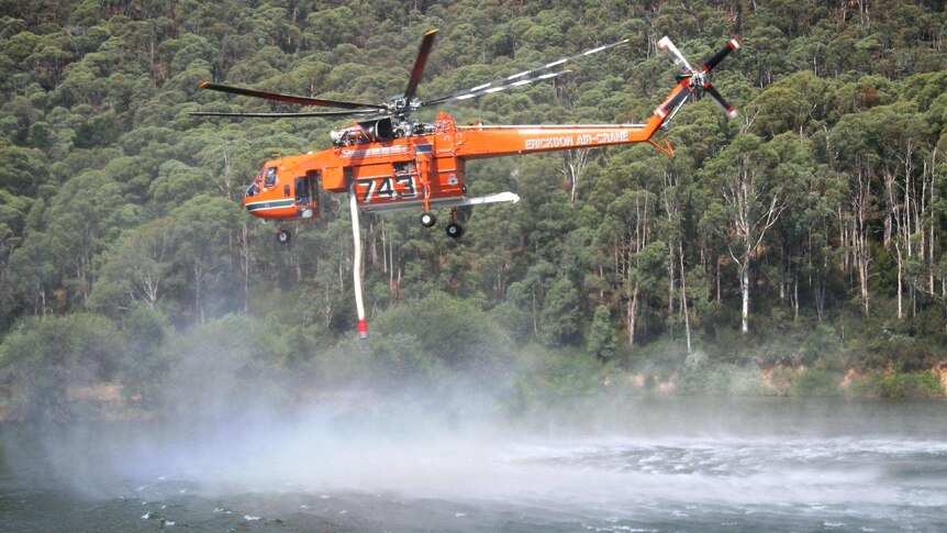 Malcolm, the Erickson Air Crane, takes off after filling up at a lake.
