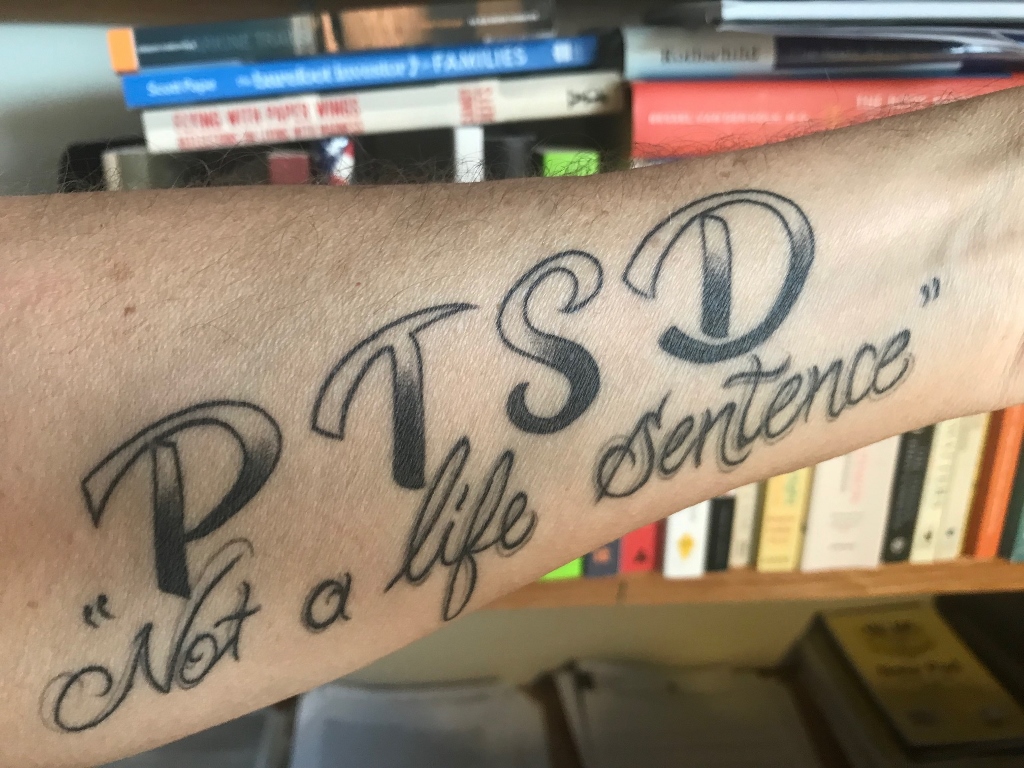 Tattoo on an arm which reads PTSD Not a life sentence