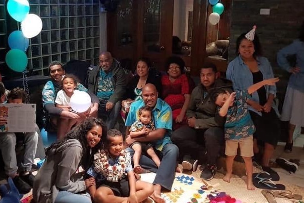 A family of 15 in celebration with balloons and party hats