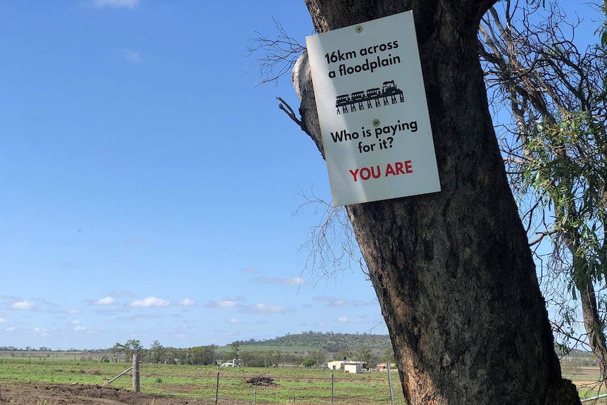 Sign on tree in a farm field that protests 16km inland rail line proposed to be built on floodplain at Millmerran