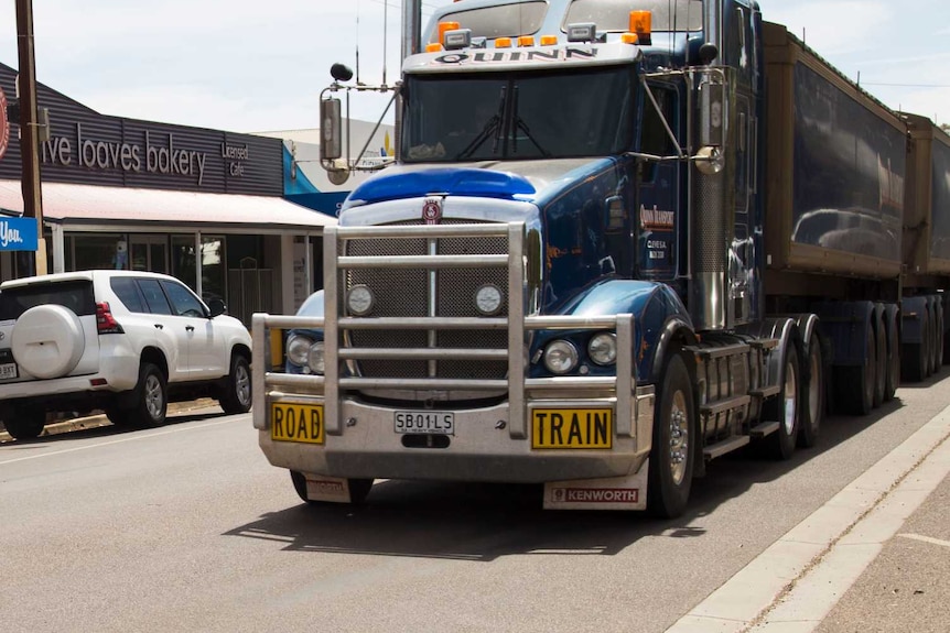 A road train is seen driving through a busy regional main street