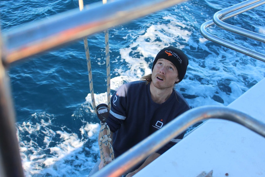 A man stands on a boat looking upwards