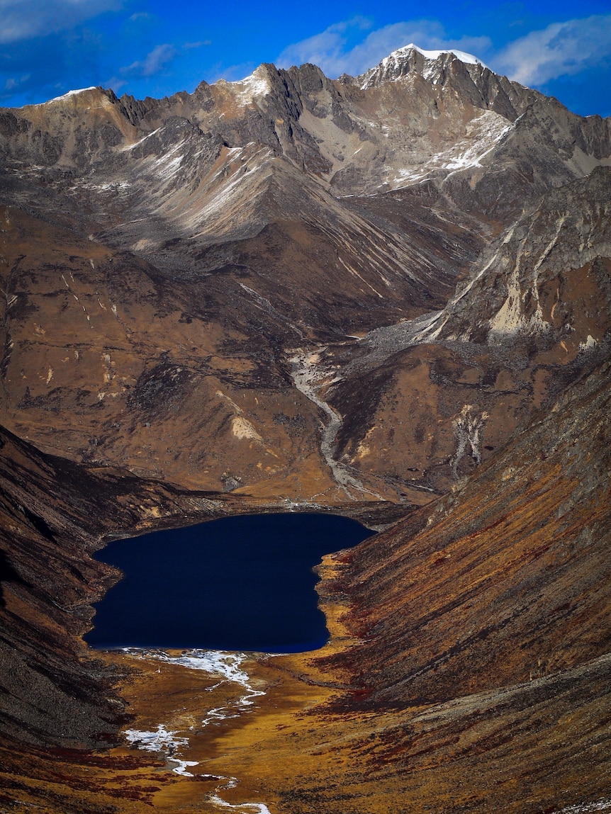 A deep blue lake is seen at the base of a mountain