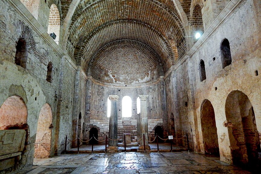 The inside of an ancient church with two large columns standing in the center.