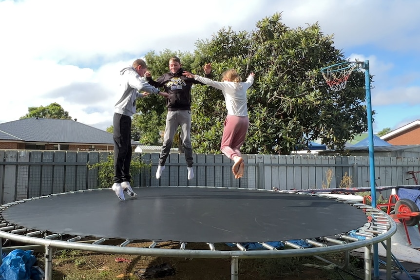three kids jumping on a trampoline 