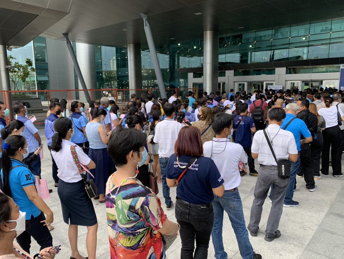 Lines of Thai people standing outside a building