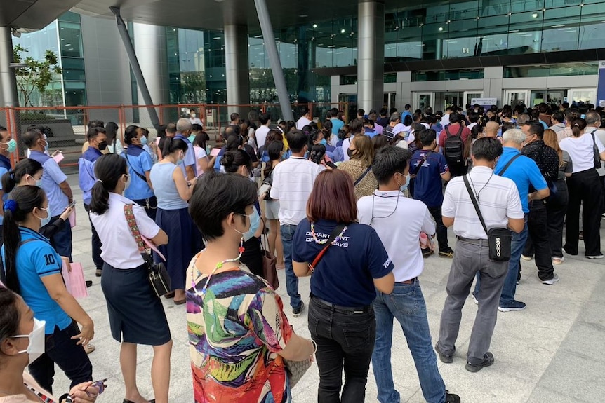 Lines of Thai people standing outside a building