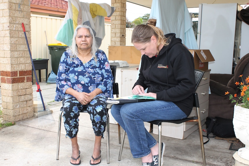 Patricia and Jenny sit on chairs, Jenny looks at a notepad.