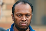 A close up of Aswath wearing a dark blue t-shirt, with tears streaming down his face.