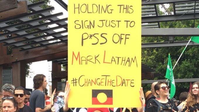 Woman holding a sign saying: "Holding this sign just to p*ss off Mark Latham"