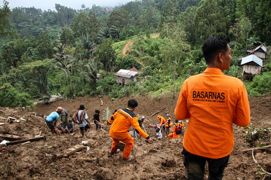 Indonesian rescue members and residents evacuate people from the site of a landslide.