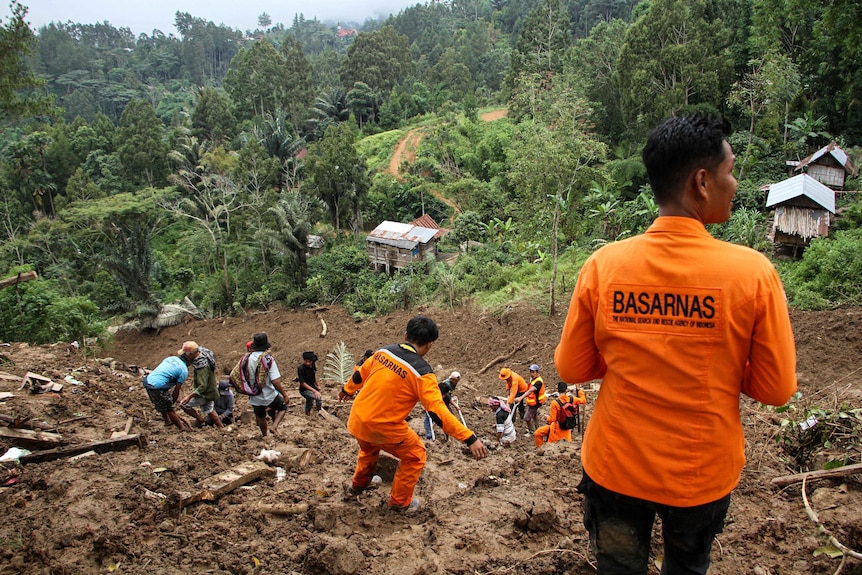 Indonesian rescue members and residents evacuate people from the site of a landslide.