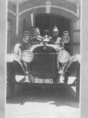 Black and White photo from 1931 of two members of Golden Square Fire Brigade in a vintage vehicle.