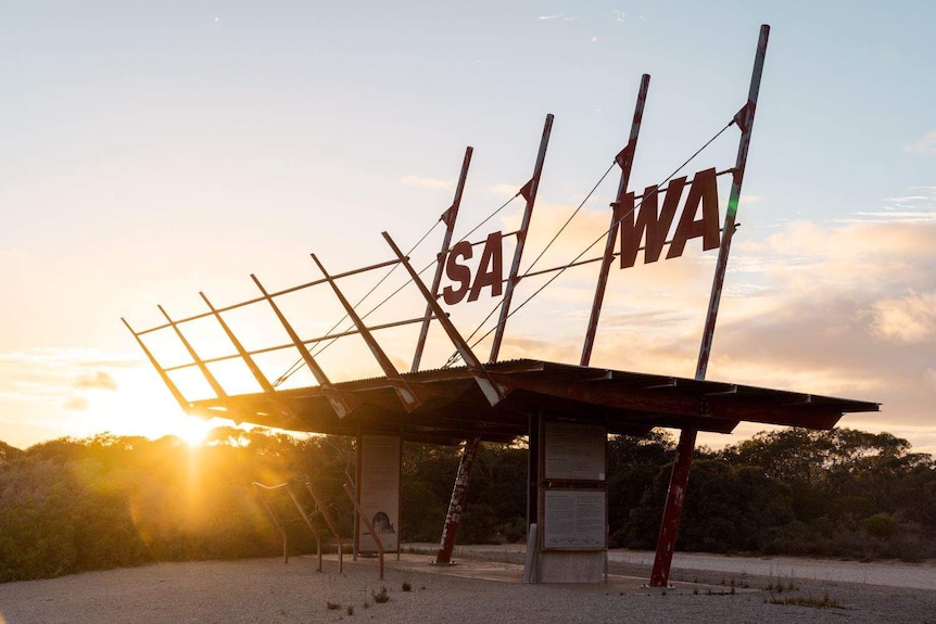 A sign at the SA and WA border at dusk.