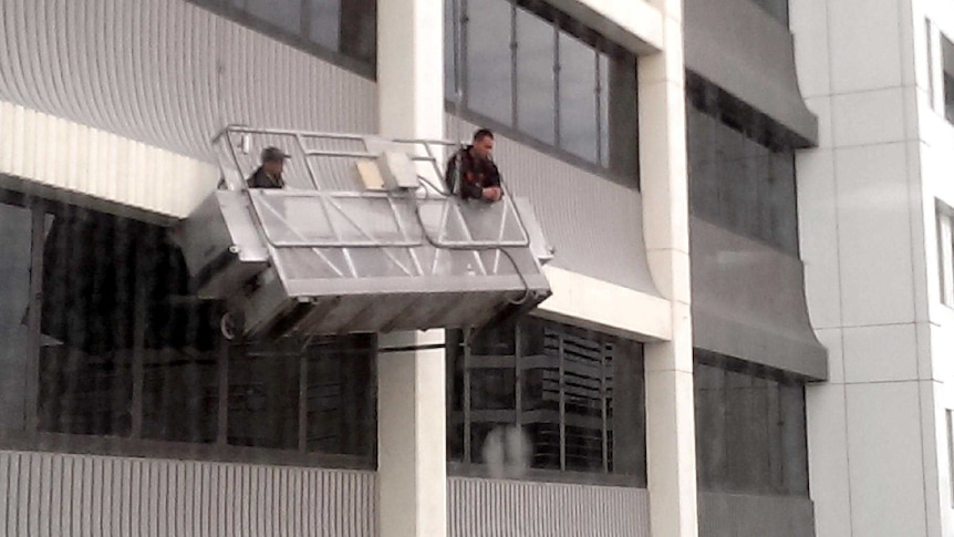 Two window cleaners wait to be rescued after their platform lost power.
