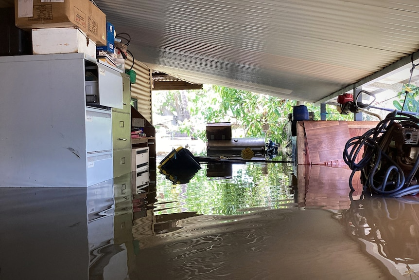 Brown murky flood water rises among a house patio
