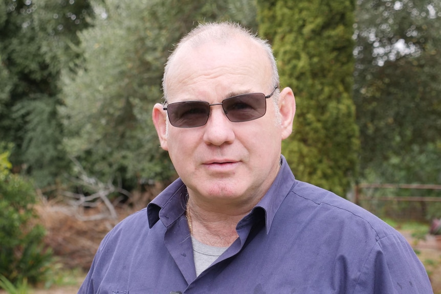 A man in sunglasses standing in a garden.