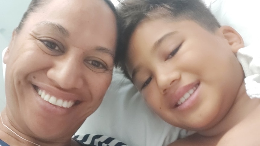 Mum Emma lies beside her son Tureti in a hospital bed.