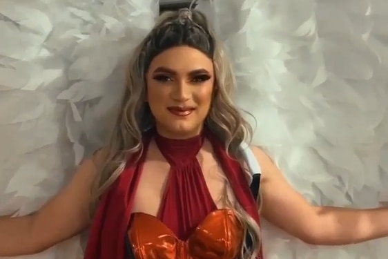 drag performer wearing angel wings in a red corset for Mardi Gras 2024