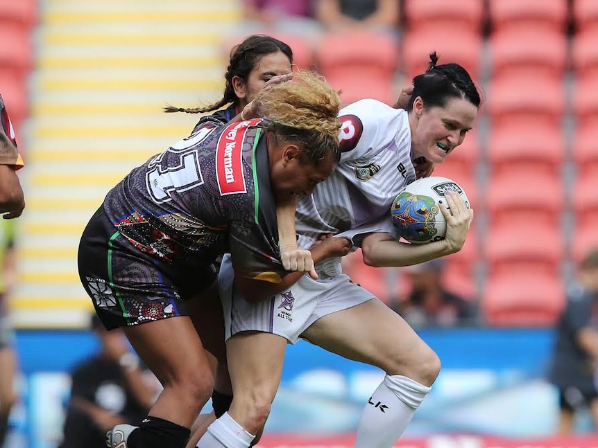 Two players attempt to tackle Chelsea Baker, who has the ball
