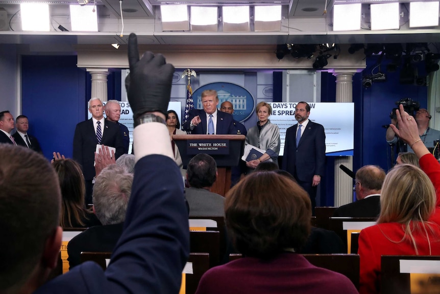 Donald Trump at a press conference with a reporter holding up his hand while wearing a latex glove