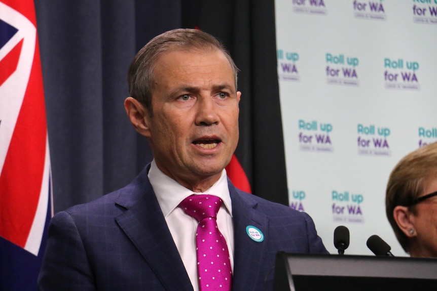 Headshot of Roger Cook with flag behind him.