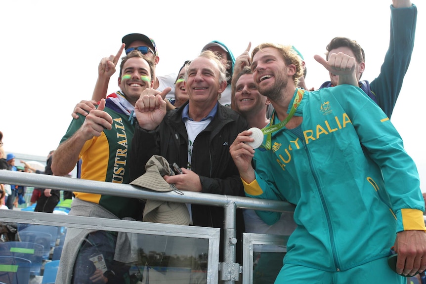 A group of men celebrating a medal in a rowing event.