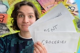 Journalist Rachel Rasker holds up envelopes labelled 'groceries' and 'rent,' making an exasperated expression.