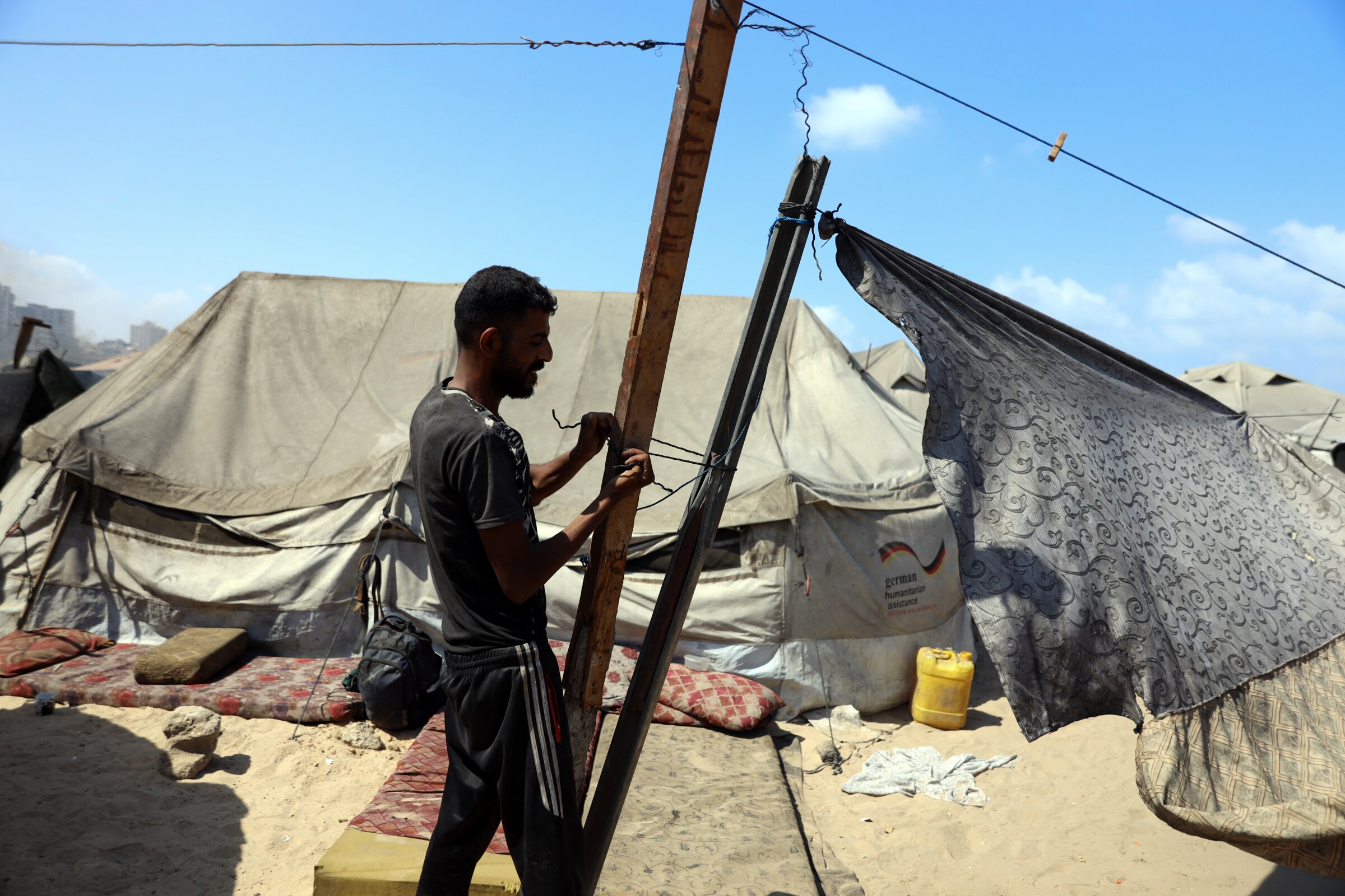 A man tying two poles together using some rope