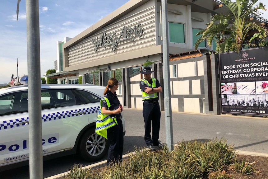 Police get out of a four-wheel drive in front of a pub