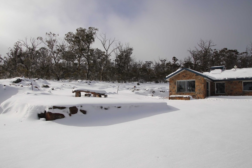 A stone house blanketed and surrounded by snow