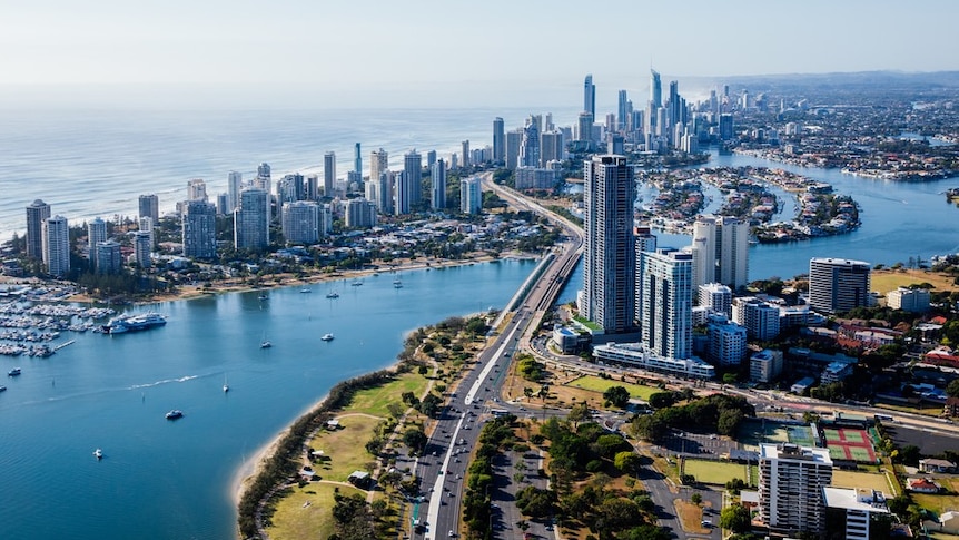 An aerial image showing a waterway, the Gold Coast skyline and the ocean behind on a clear, sunny day.