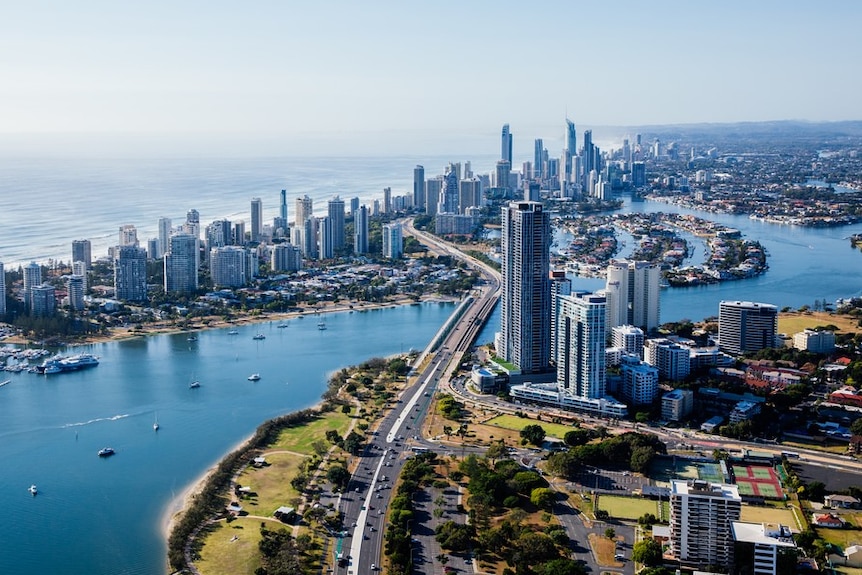 An aerial image showing a waterway, the Gold Coast skyline and the ocean behind on a clear, sunny day.