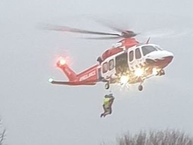 Someone being winched out of floodwaters by a helicopter