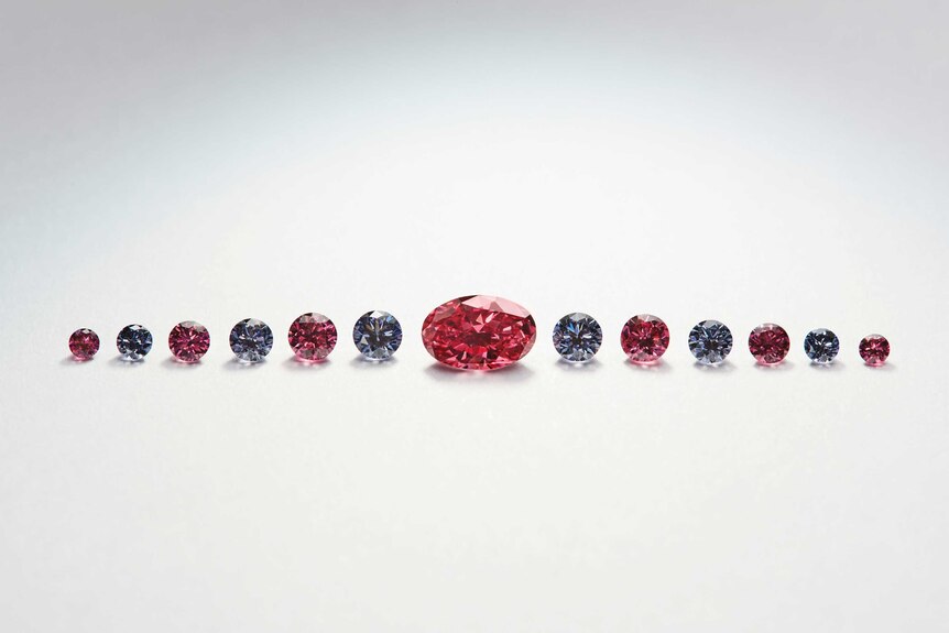 A line of tiny pink, red and violet diamonds in a row against white backdrop