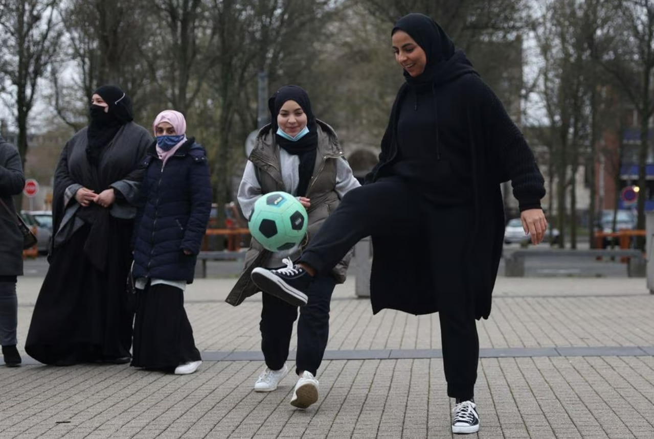 Women kicking around a bright green soccer ball