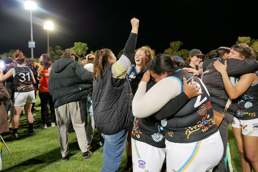 A group of women celebrates on a field