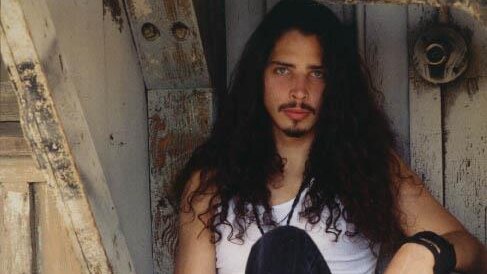 An undated photograph of young Chris Cornell sitting in a doorway with his guitar case
