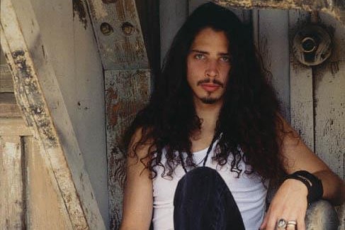 An undated photograph of young Chris Cornell sitting in a doorway with his guitar case