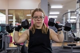Julie Dickson lifts one small weight with each hand, to above her shoulders.